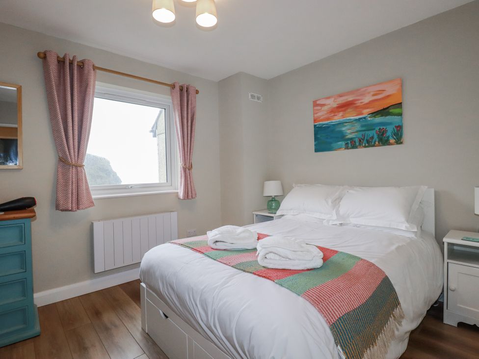 A bedroom with a bed and window at Kippy Cottage in Porthtowan