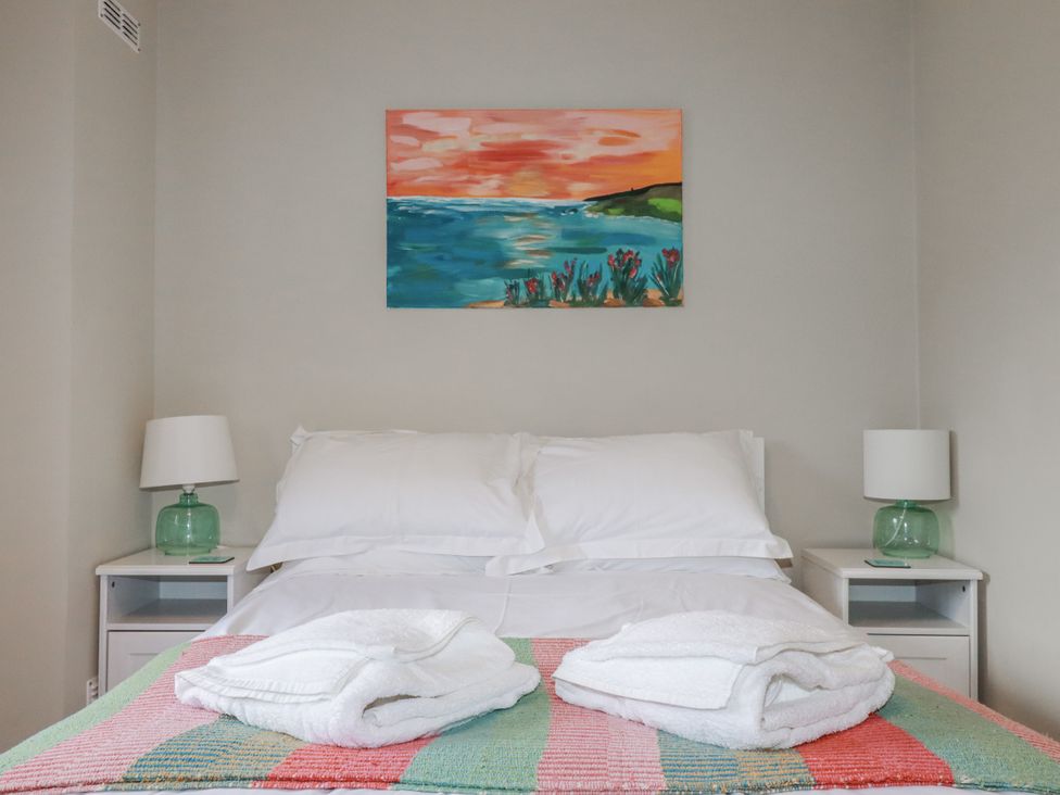 A bedroom with a bed and nightstands at Kippy Cottage Porthtowan