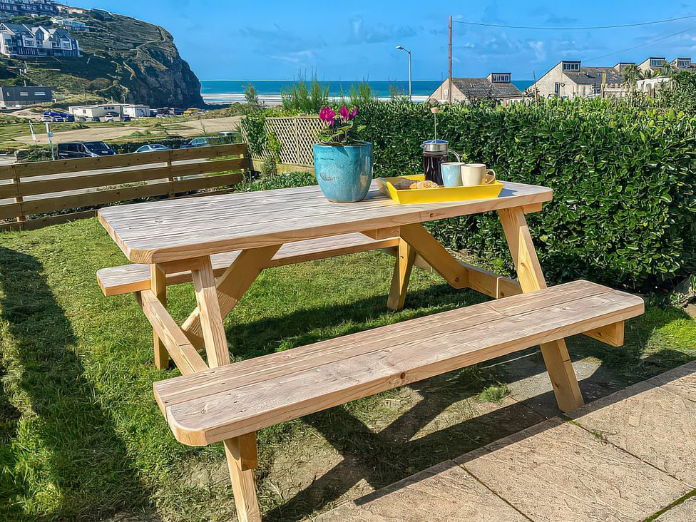 A table with benches and a plant pot at Kippy Cottage in Porthtowan