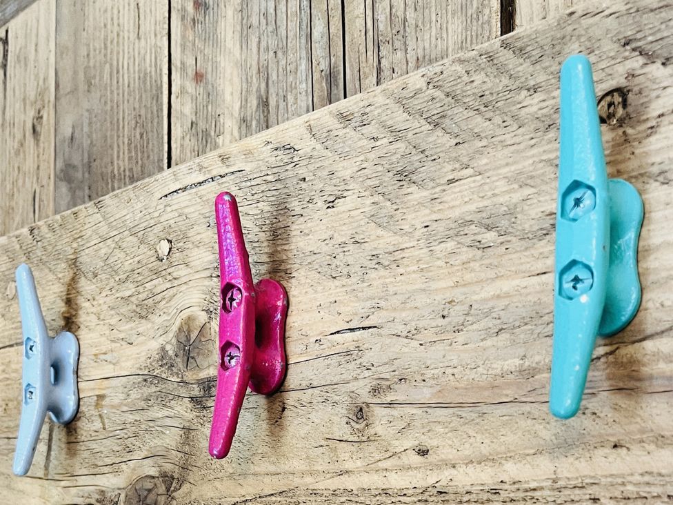 Three colored hooks on a wooden panel at Kippy Cottage Porthtowan