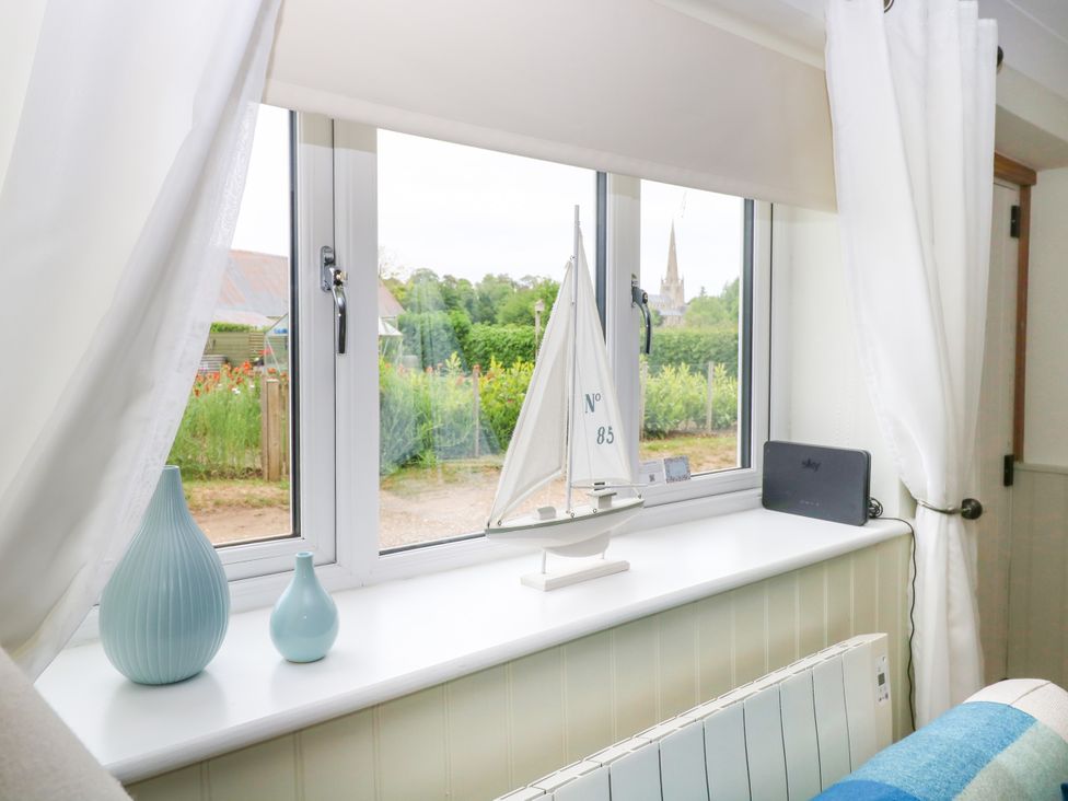 A window sill with two blue vases a model sailboat and a sky device at Herbies Cottage in Snettisham