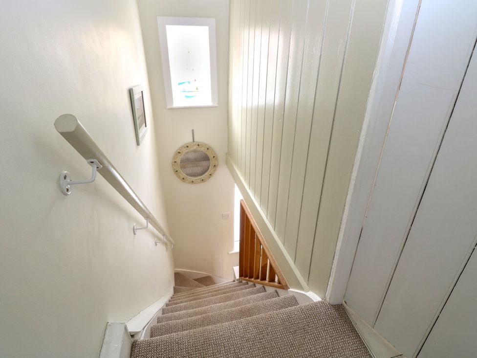 A carpeted staircase with a white handrail and a round mirror on the wall at Herbies Cottage in Snettisham