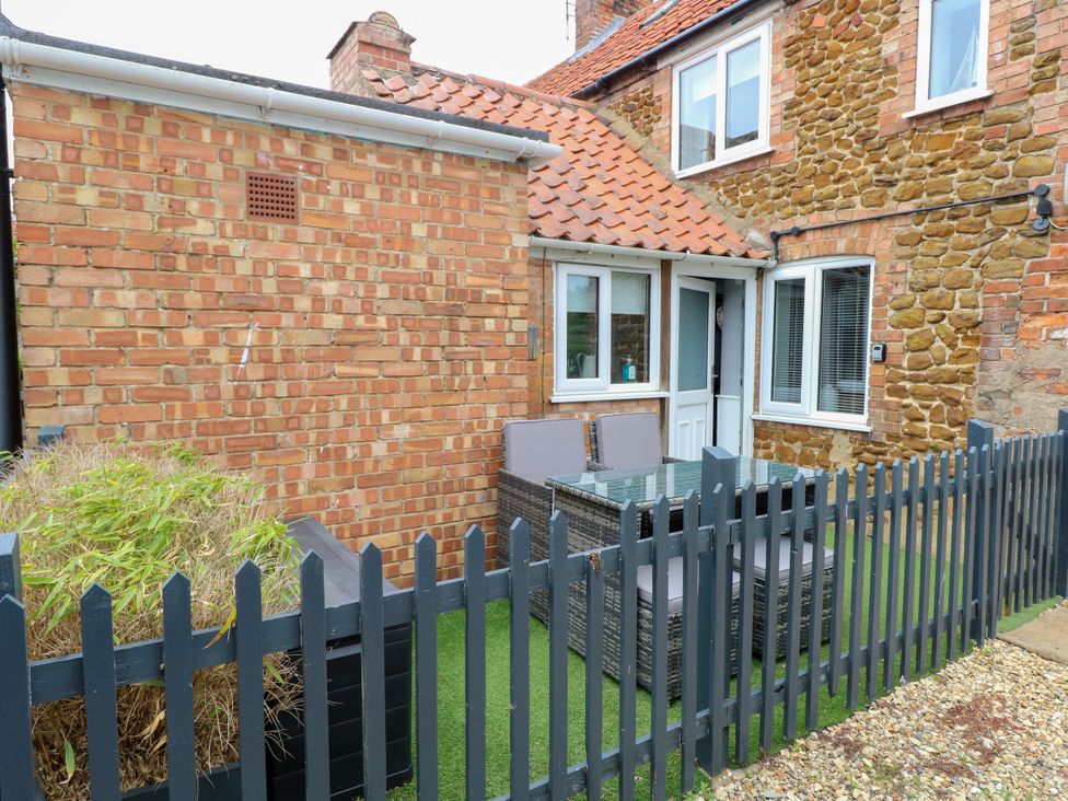 A fenced outdoor patio area with a table and chairs next to a brick and stone house