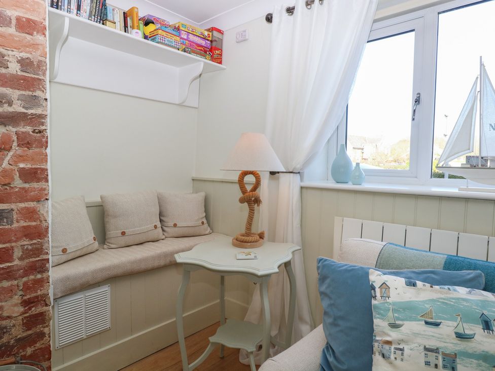 A snug with a seating area and shelf for games at Herbies Cottage in Snettisham