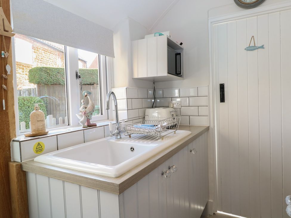 A kitchen with a sink and dish rack at Herbies Cottage in Snettisham