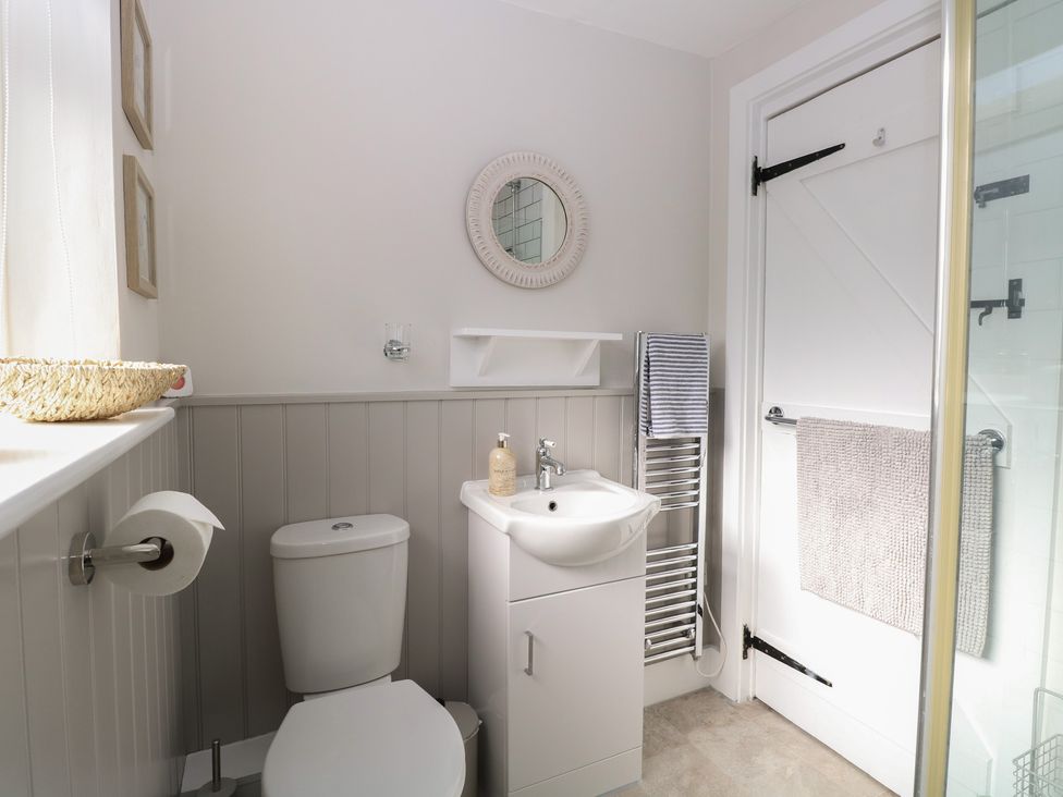 A bathroom with a toilet, hand basin, and towel rail at Herbies Cottage in Snettisham