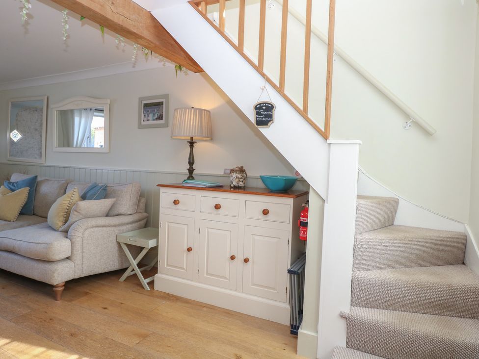 A living room with a sofa and stairs at Herbies Cottage in Snettisham
