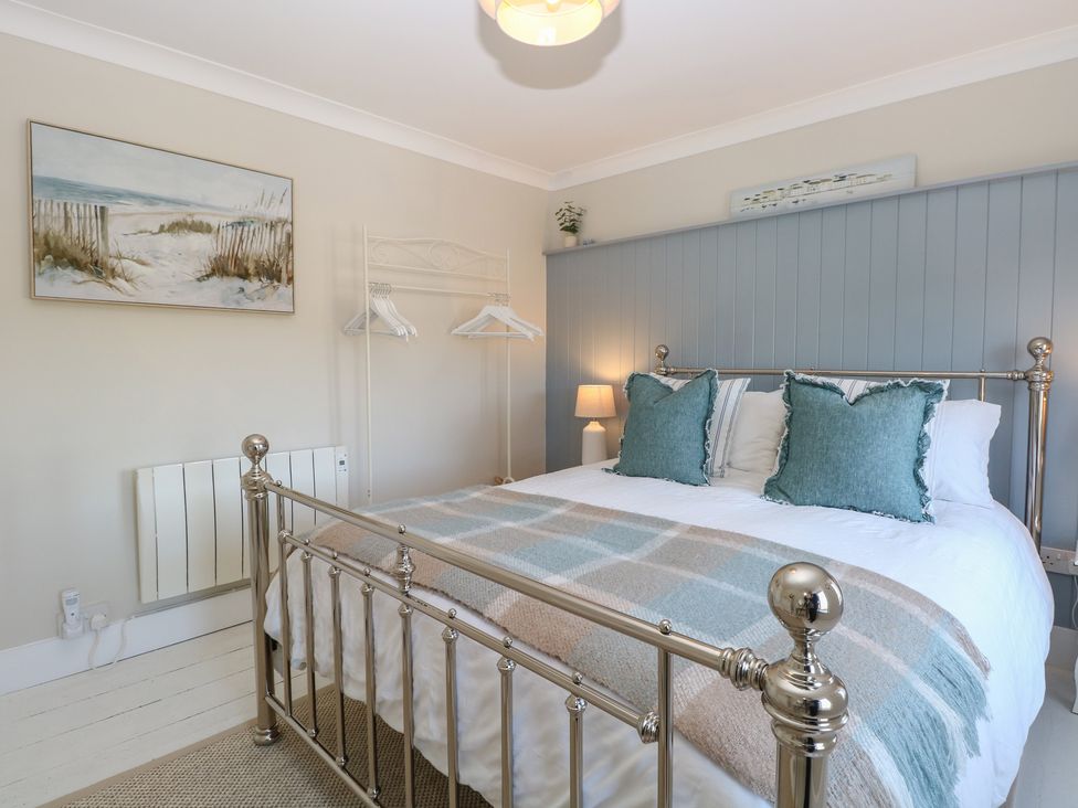 A bedroom with a bed and wall art at Herbies Cottage in Snettisham