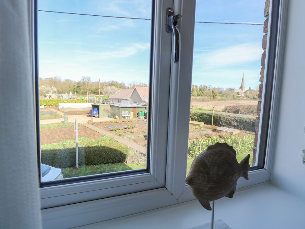 A view of a garden and house from a window at Herbies Cottage in Snettisham