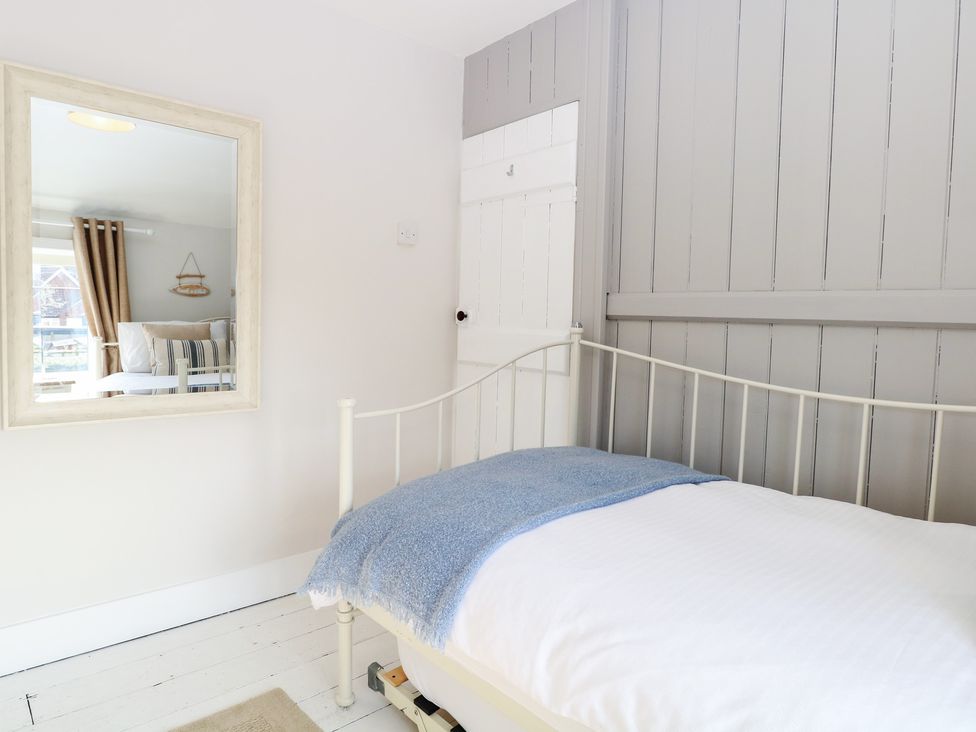 A bedroom with a bed and mirror at Herbies Cottage in Snettisham