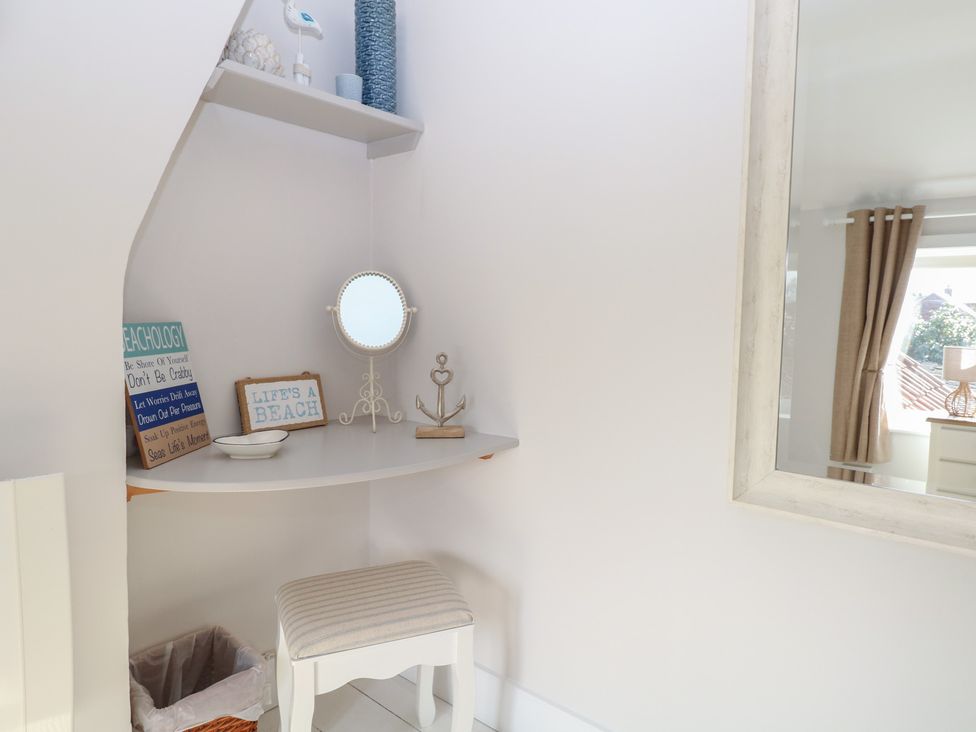 A dressing area with a mirror and shelf at Herbies Cottage in Snettisham