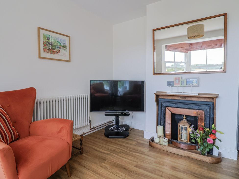 A living room with a TV and a fireplace at St Helena in Charmouth