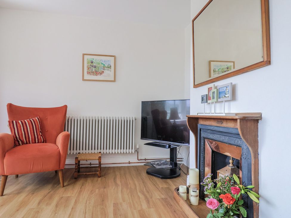 A living room with an armchair and fireplace at St Helena in Charmouth