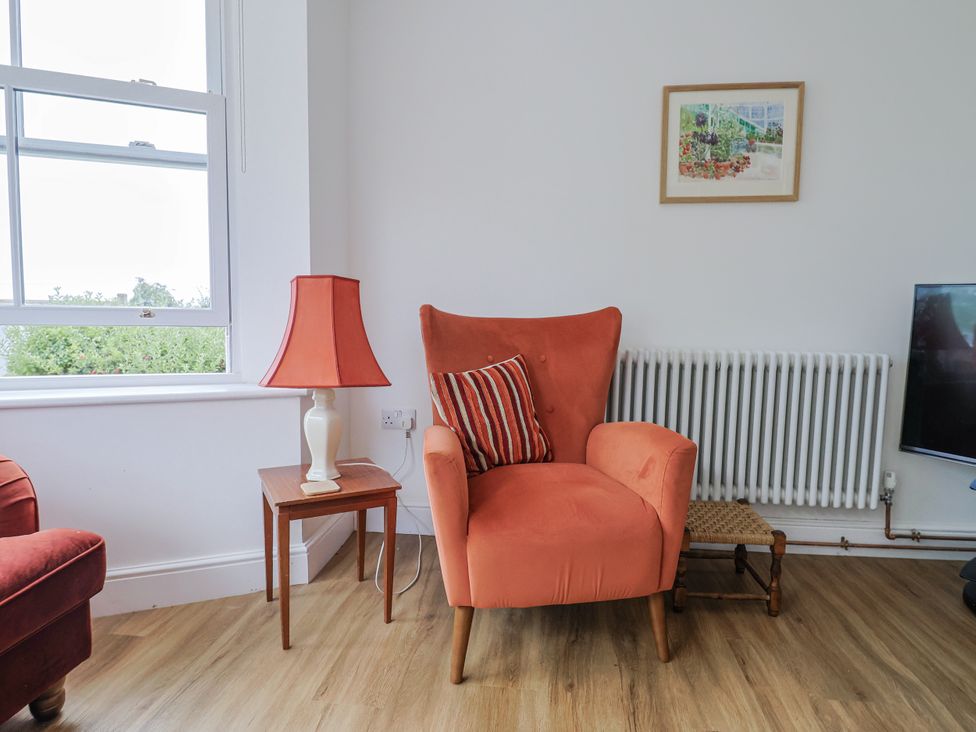 A living room with an armchair and lamp at St Helena in Charmouth