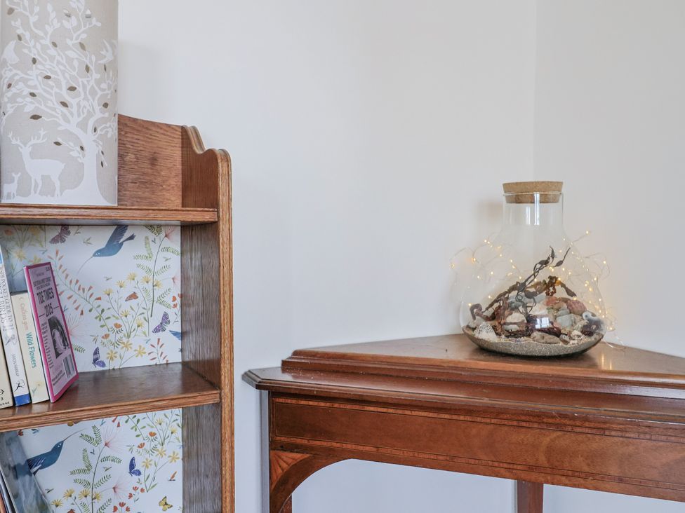 A bookshelf and a table with a glass jar at St Helena in Charmouth