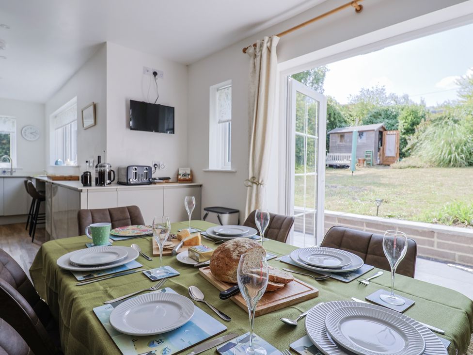A dining room with a table set for a meal at St Helena in Charmouth