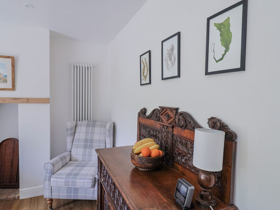 A living room with a chair and a wooden table at St Helena in Charmouth