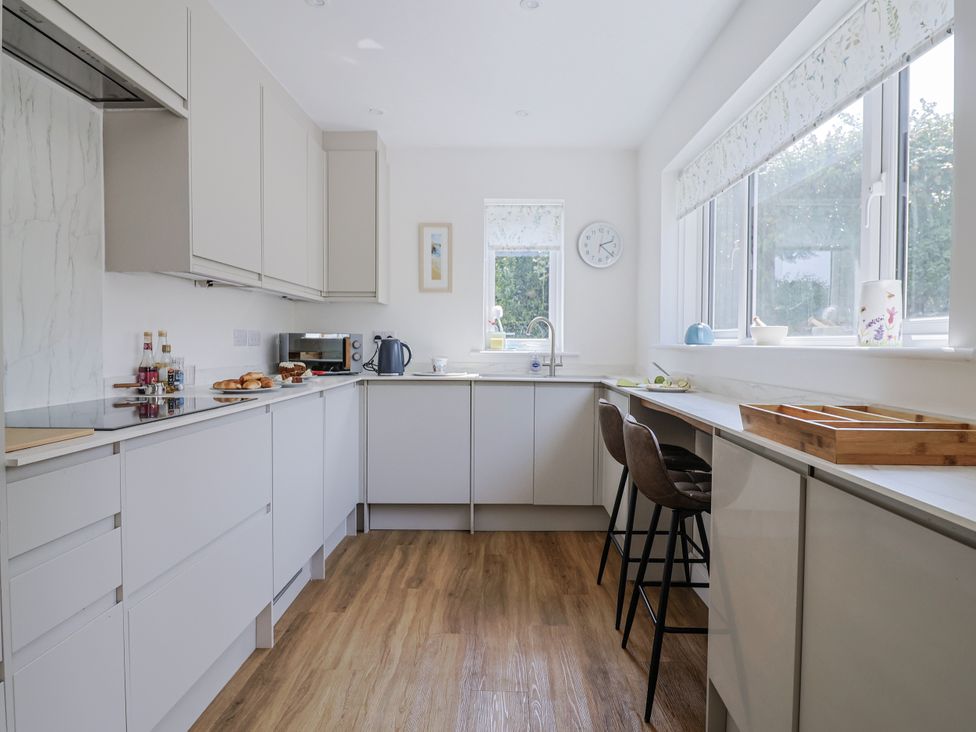 A kitchen with cabinets, counter space, and bar stools at St Helena in Charmouth