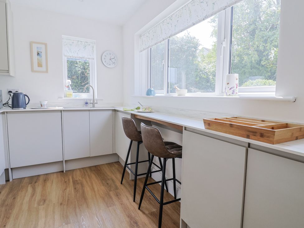 A kitchen with a sink and bar stools at St Helena in Charmouth