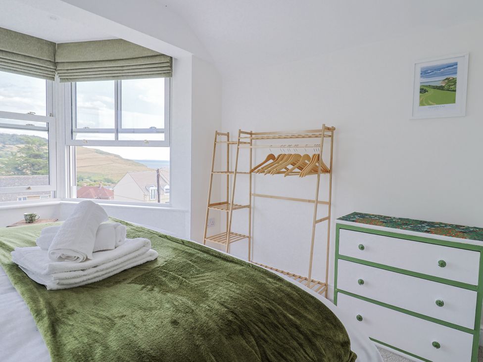 A bedroom with a bed and a clothing rack at St Helena in Charmouth