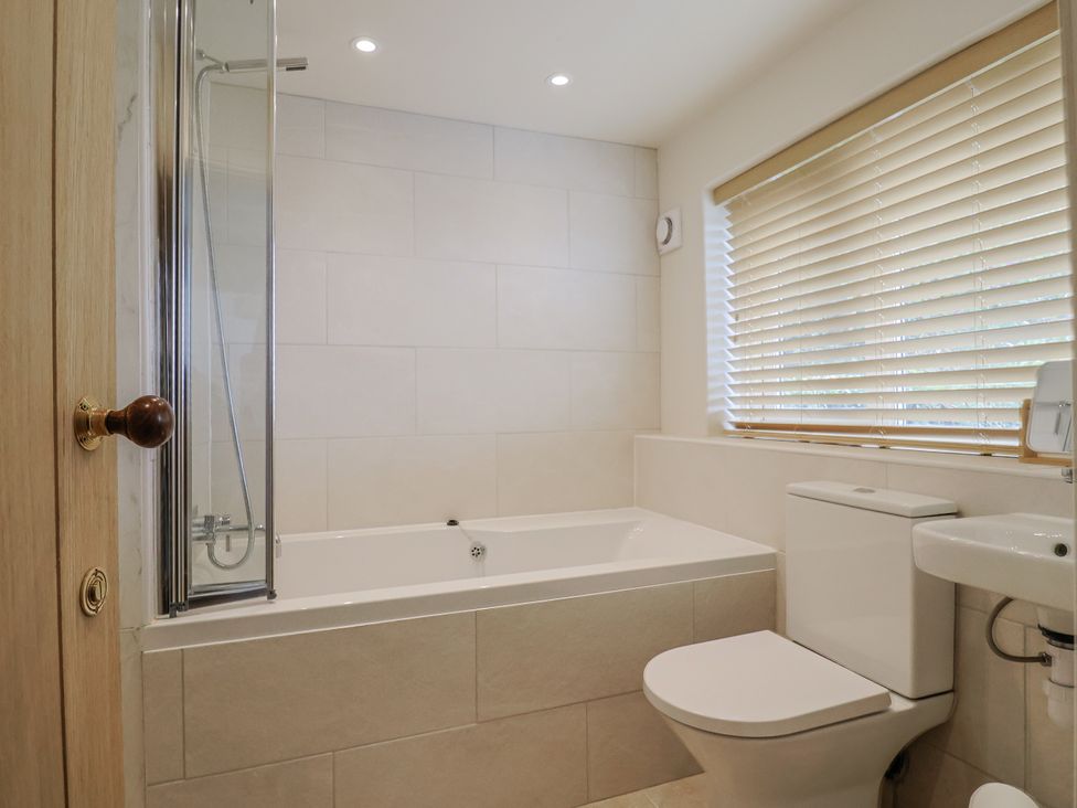 A bathroom with a bath tub, toilet, and sink at St Helena in Charmouth