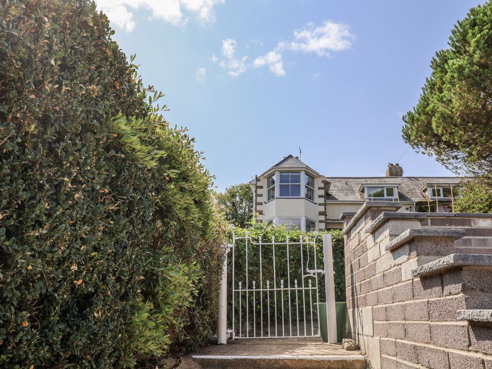 A gate leading to a house with hedges at St Helena in Charmouth