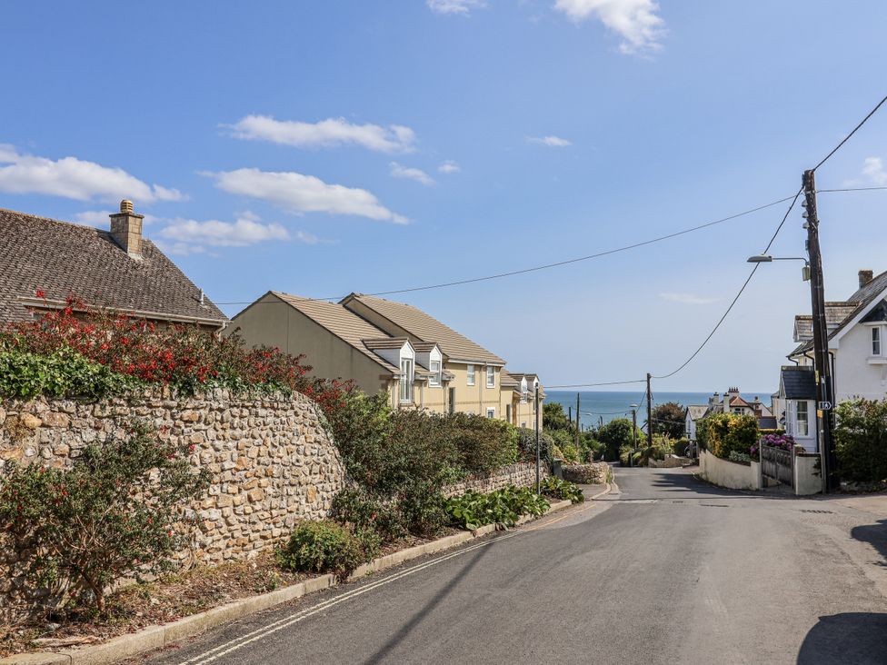 A street view with houses and a stone wall at St Helena in Charmouth