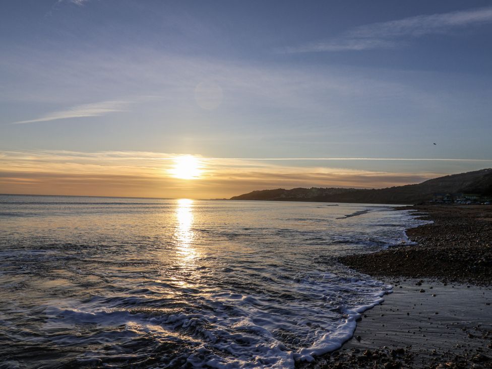 A beach with waves and a sunset at St Helena in Charmouth