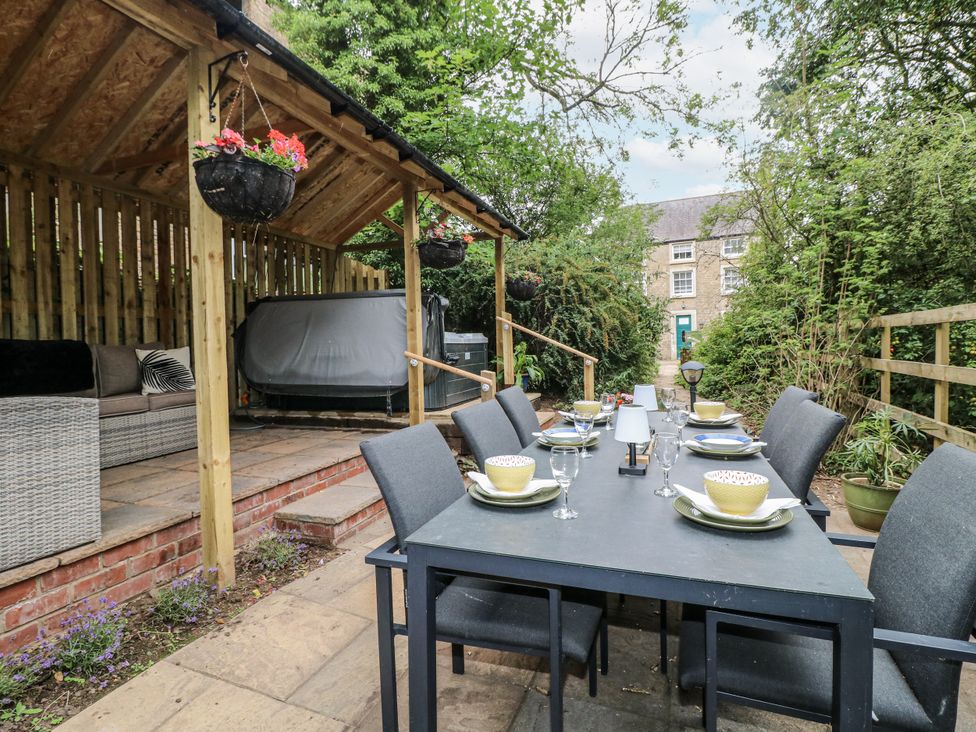 An outdoor dining area with table settings and a hot tub at Mill View Duplex in Cuckney