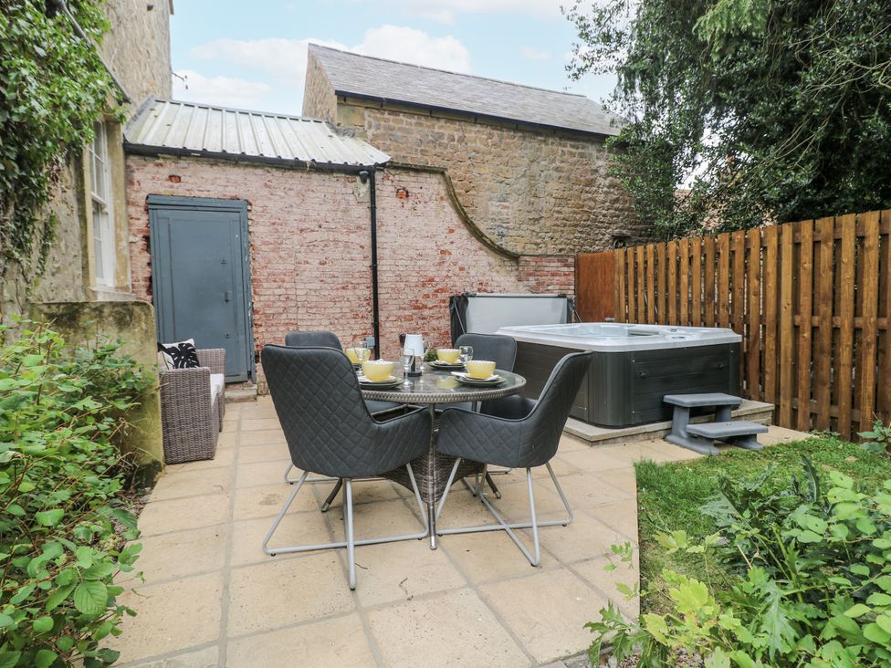 A garden area with a dining set and hot tub at Cotton Mill Cottage in Cuckney