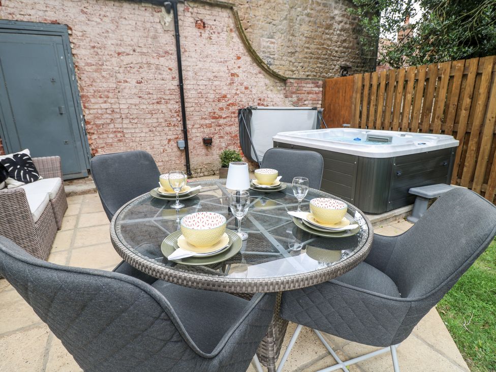 A dining area with a table and chairs next to a hot tub at Cotton Mill Cottage Cuckney