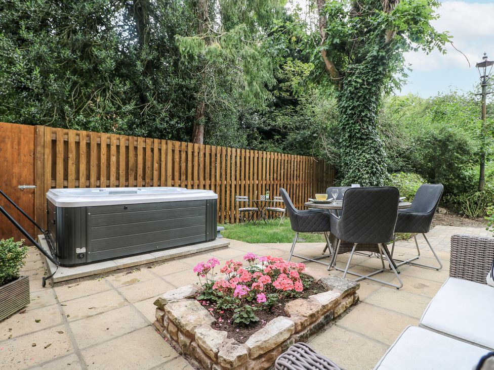 A garden with a hot tub and outdoor dining set at Cotton Mill Cottage Cuckney