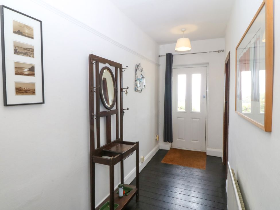 A hallway with a coat rack and photographs at Faraway in Rhosneigr