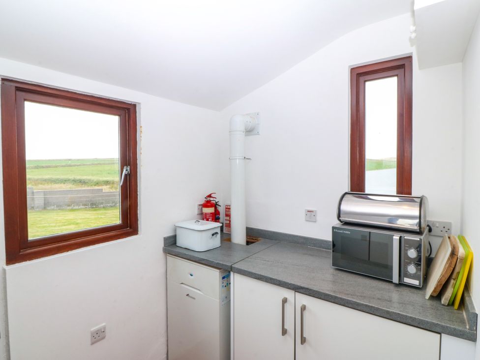 A kitchen with a microwave and bread bin at Faraway in Rhosneigr