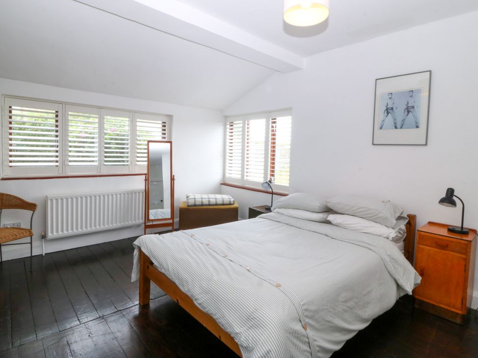 A bedroom with a bed and mirror at Faraway in Rhosneigr