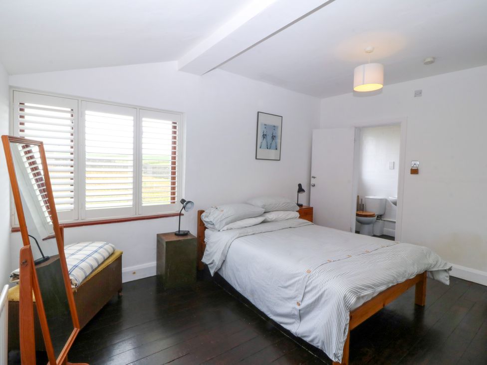 A bedroom with a bed and a mirror at Faraway in Rhosneigr