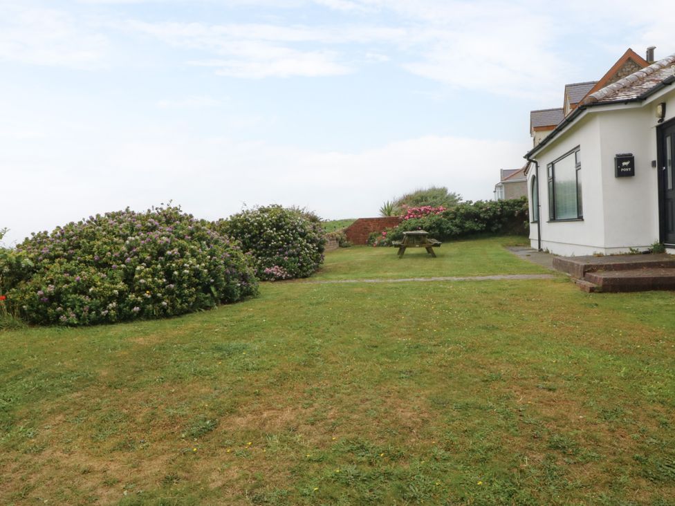 A house with bushes and a table in the garden at Faraway Rhosneigr