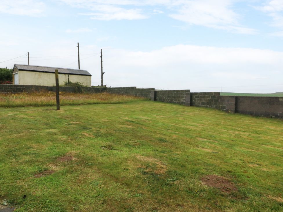 An outdoor area with grass and a building at Faraway in Rhosneigr