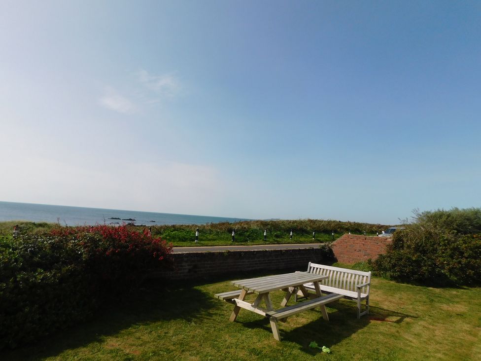 A table and benches by the ocean at Faraway in Rhosneigr