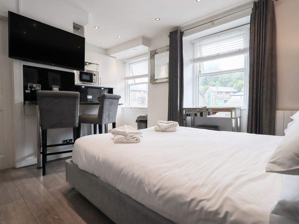 A bedroom with a bed and kitchen area at Bowness Central in Bowness-On-Windermere