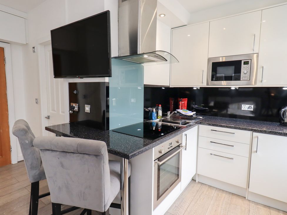 A kitchen with appliances and bar stools at Bowness Central in Bowness-On-Windermere