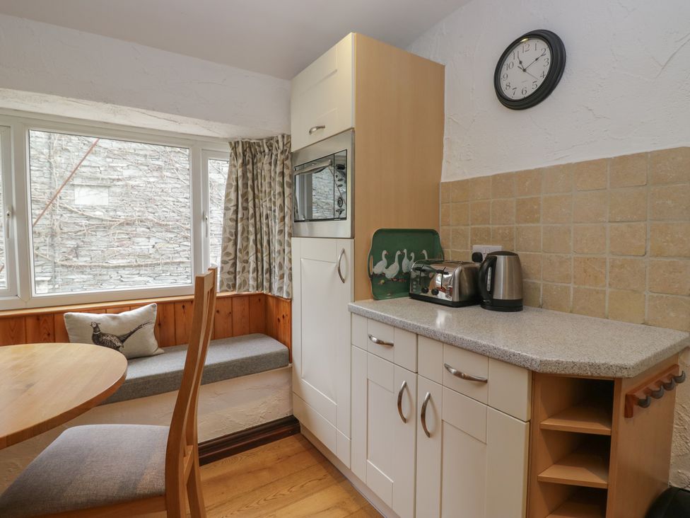 A kitchen with table, chairs, and appliances at Woodloft Cottage Elterwater near Chapel Stile