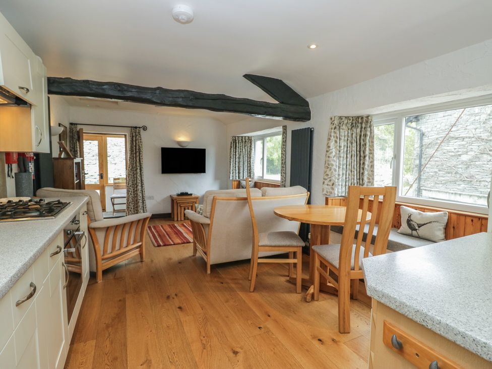 A living room with a table and chairs near the kitchen at Woodloft Cottage in Elterwater near Chapel Stile