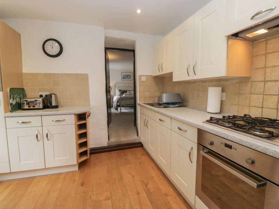 A kitchen featuring cabinets, stove, sink and doorway at Woodloft Cottage Elterwater near Chapel Stile