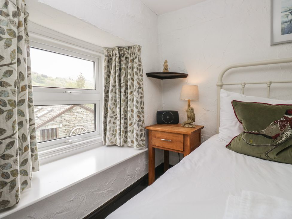 A bedroom with a window and bedside table at Woodloft Cottage Elterwater near Chapel Stile