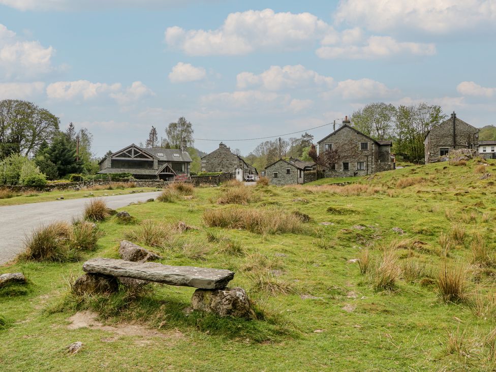 An outdoor area with stone houses and a bench at Woodloft Cottage Elterwater near Chapel Stile