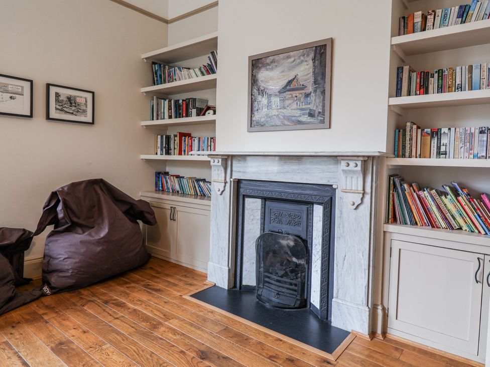 A living room with a fireplace and bookshelves at Holly Lodge in Aldeburgh