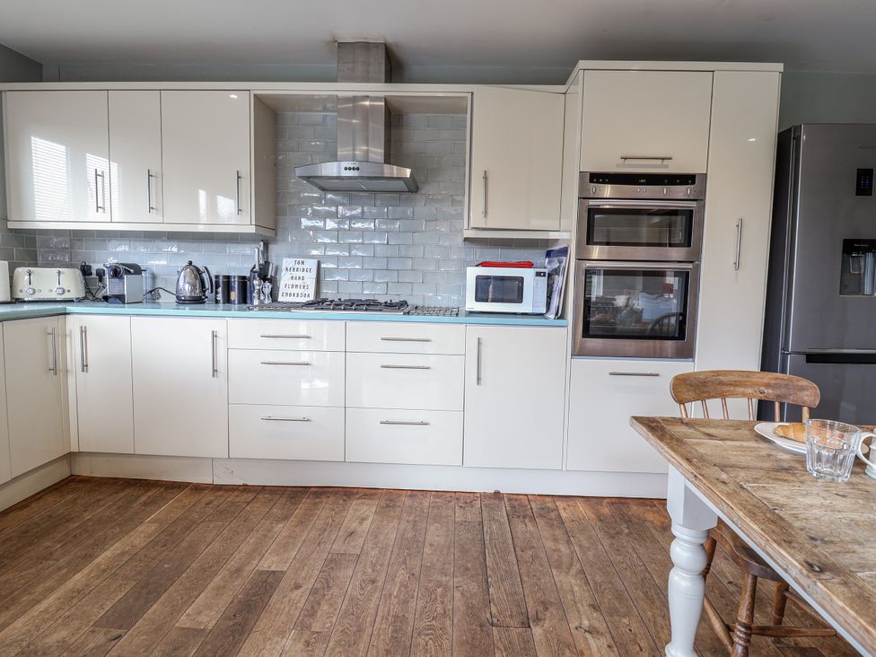 A kitchen with appliances and a dining table at Holly Lodge in Aldeburgh