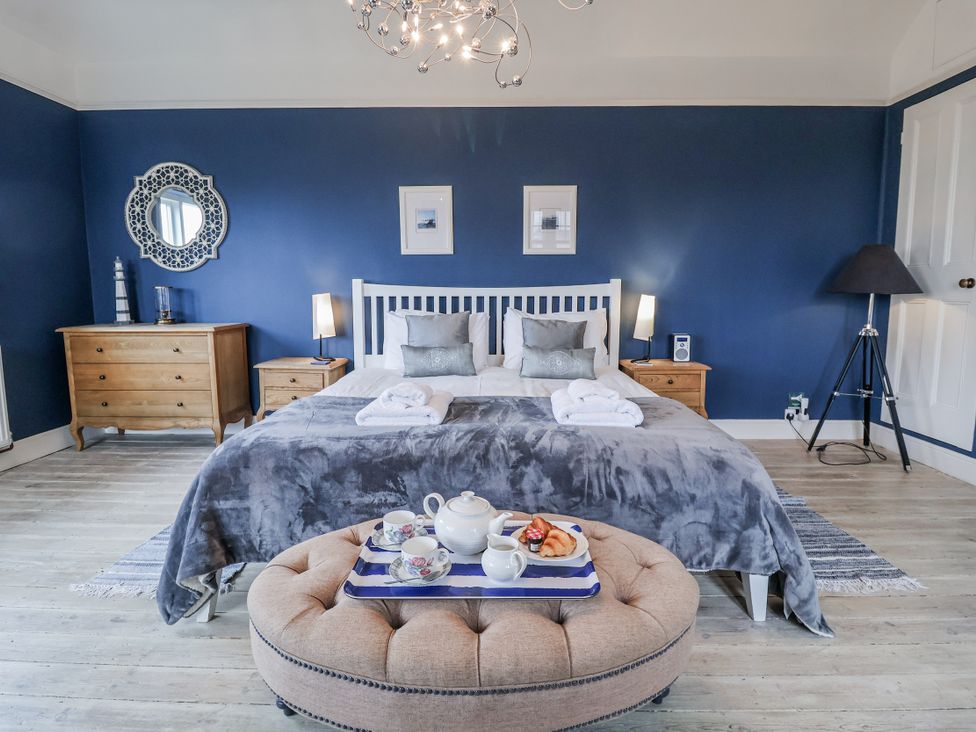 A bedroom with a bed, dresser, and tea set at Holly Lodge in Aldeburgh