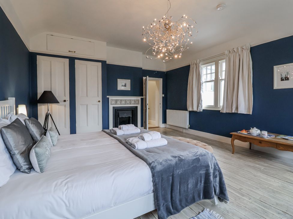 A bedroom with a bed and armchair at Holly Lodge in Aldeburgh